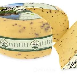 KI generiert: Das Bild zeigt einen großen, runden Käse mit einem Stück, das herausgeschnitten wurde, um die innere Struktur zu zeigen. Der Käse hat kleine Kräuter oder Gewürze in der Masse verteilt.