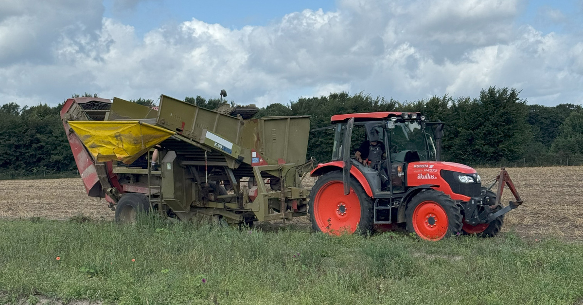 KI generiert: Ein roter Traktor zieht eine landwirtschaftliche Maschine über ein Feld.