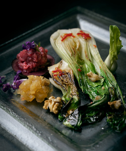 KI generiert: Das Bild zeigt ein Dessert im Glas, das mit einer Löffelportion Croquant und einem Blatt grüne Dekoration versehen ist. Im Hintergrund ist unscharf grüne Dekoration sichtbar.