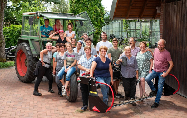 KI generiert: Eine Gruppe von Menschen posiert lächelnd vor einem Traktor.