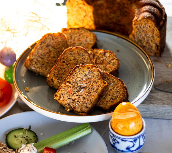KI generiert: Ein Teller mit geschnittenem Körnerbrot und ein dekoriertes Ei im Vordergrund.