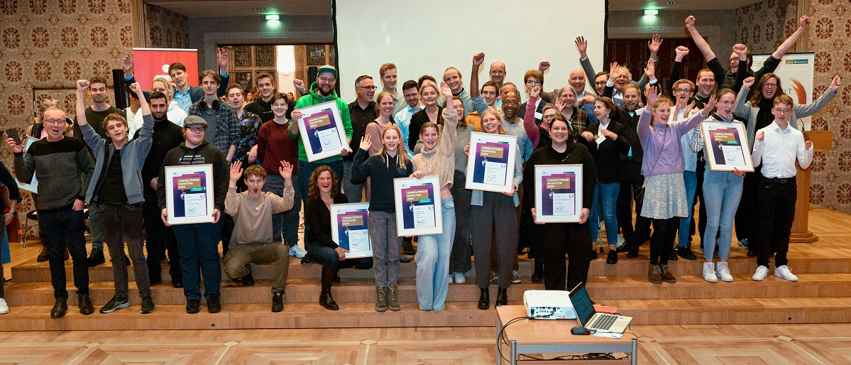 KI generiert: Eine Gruppe von Menschen steht auf einer Bühne, einige halten gerahmte Zertifikate oder Auszeichnungen in den Händen. Sie wirken fröhlich und jubeln in einer feierlichen Atmosphäre.