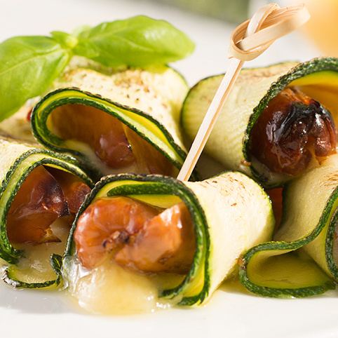 KI generiert: Zucchini-Röllchen mit Kirschtomaten und Käse, garniert mit Basilikum.
