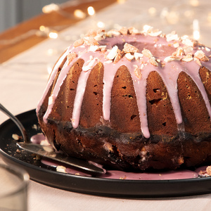 KI generiert: Das Bild zeigt ein Dessert im Glas, das mit einer Löffelportion Croquant und einem Blatt grüne Dekoration versehen ist. Im Hintergrund ist unscharf grüne Dekoration sichtbar.
