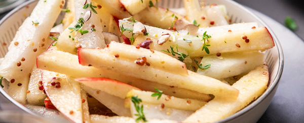 KI generiert: Ein Teller mit Apfel- und vielleicht Selleriesticks, garniert mit Kräutern und Senfkörnern.