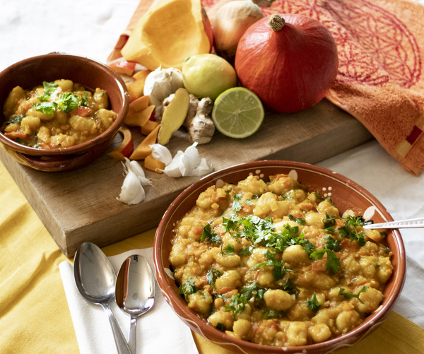 KI generiert: Zwei Schalen mit einem Curry-Gericht und frischen Zutaten auf einem Tisch.