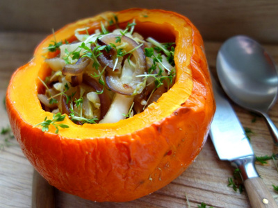 KI generiert: Das Bild zeigt einen in zwei Hälften geschnittenen Butternut-Kürbis auf einem Holzschneidebrett mit herzförmiger Aussparung. Der Kürbis ist leuchtend orange und hat sichtbare Kerne.