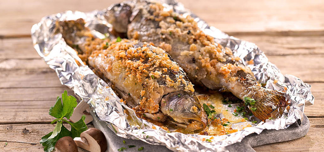 KI generiert: Das Bild zeigt ein Dessert im Glas, das mit einer Löffelportion Croquant und einem Blatt grüne Dekoration versehen ist. Im Hintergrund ist unscharf grüne Dekoration sichtbar.