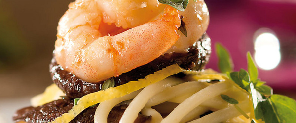 KI generiert: Ein kunstvoll angerichtetes Gericht mit Garnelen, Nudeln und Kräutern.