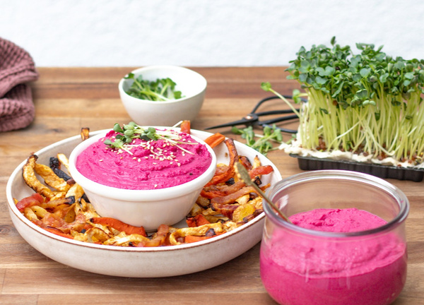 KI generiert: Ein Teller mit Rote-Bete-Hummus und Gemüse, daneben frische Sprossen.