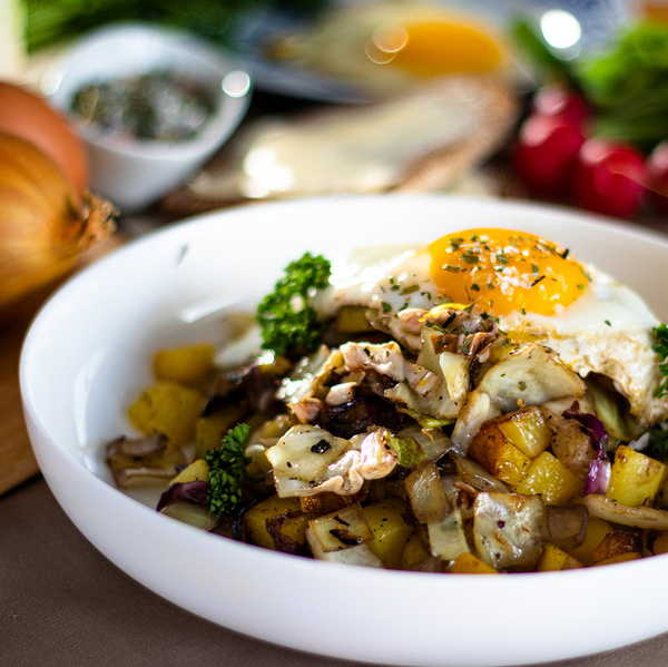 KI generiert: Ein Teller mit Bratkartoffeln, Gemüse und Spiegelei, dekoriert mit Kräutern.