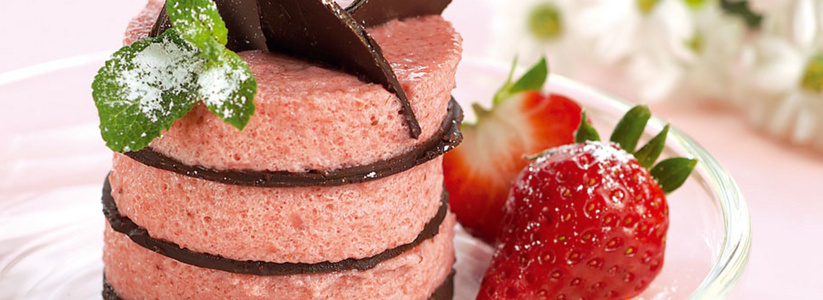 KI generiert: Ein Glas Schokoladenmousse, garniert mit Beeren und Minze, auf einem rustikalen Holztisch.