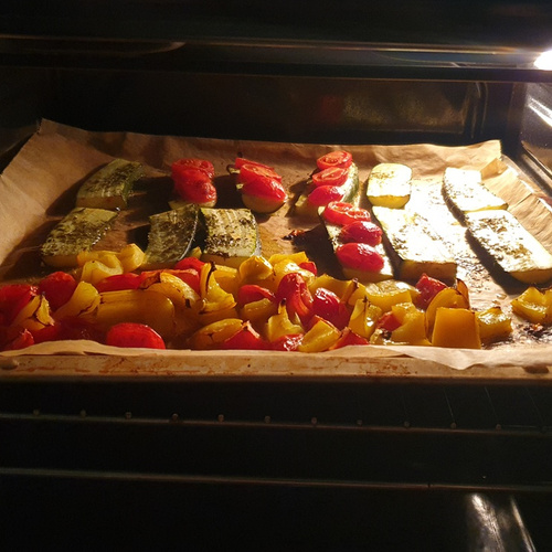 KI generiert: Gebackenes Gemüse im Ofen auf einem Backblech: Zucchini, Paprika und Tomaten.