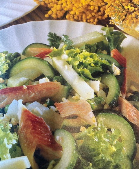 KI generiert: Ein frischer Salat mit Gurken, Blattsalat und Ziegenkäse, dekoriert mit gelben Blumen im Hintergrund.