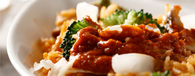 KI generiert: Das Bild zeigt ein Dessert im Glas, das mit einer Löffelportion Croquant und einem Blatt grüne Dekoration versehen ist. Im Hintergrund ist unscharf grüne Dekoration sichtbar.