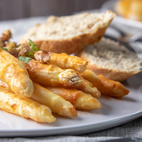 KI generiert: Spargel auf einem Teller mit Brot im Hintergrund.