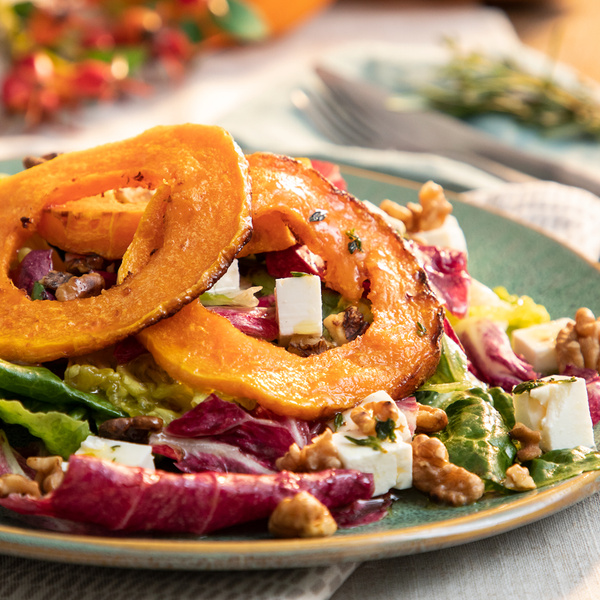 KI generiert: Salat mit geröstetem Kürbis, Feta, Walnüssen und Blattsalat auf einem Teller.