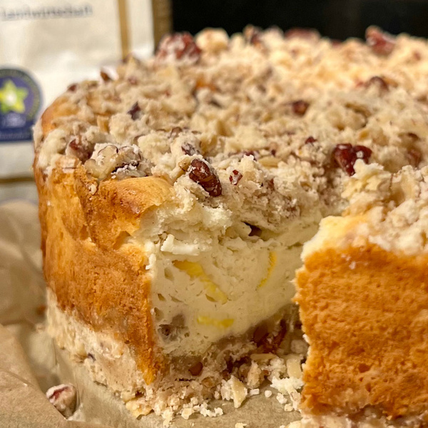 KI generiert: Ein angeschnittener Kuchen mit Streuseln und Nüssen auf der Oberseite.