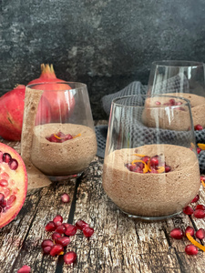 KI generiert: Ein Glas Schokoladenmousse, garniert mit Beeren und Minze, auf einem rustikalen Holztisch.