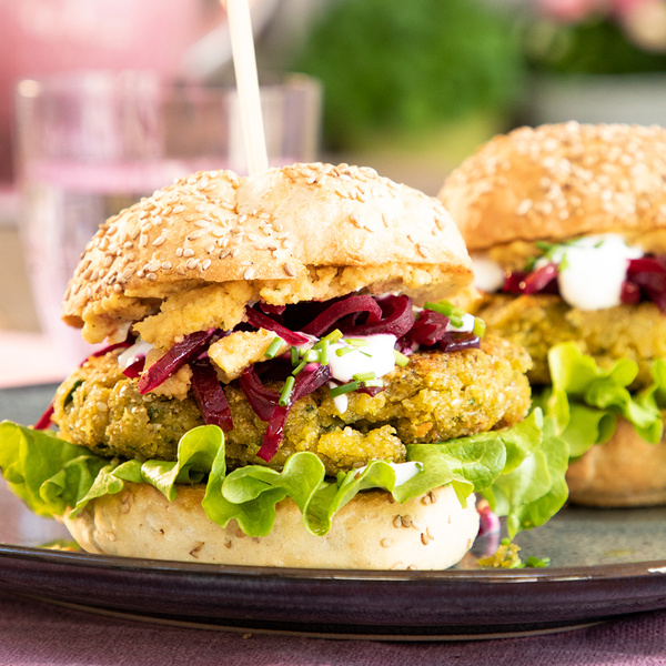 KI generiert: Ein Veggie-Burger mit Salat, Rote Bete, Kichererbsenpatty und Sesam-Brötchen auf einem Teller.