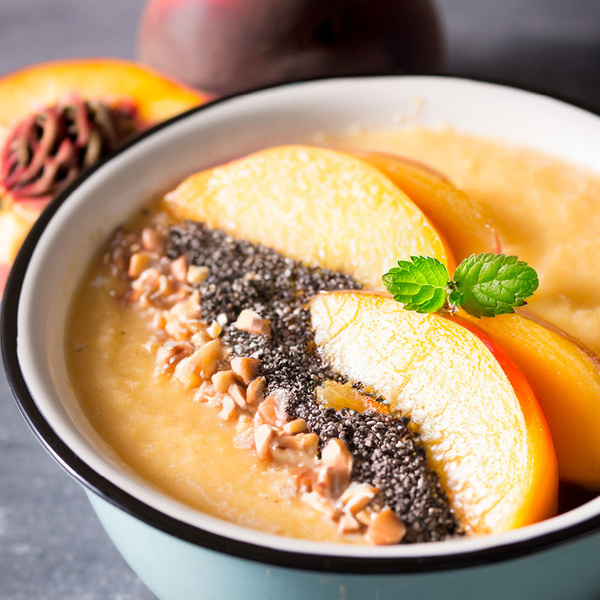 KI generiert: Eine Schale mit Pfirsich-Smoothie, Chiasamen, Nüssen und frischen Pfirsichscheiben.