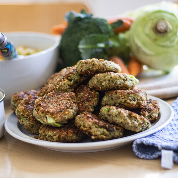 KI generiert: Ein Teller mit Gemüsebratlingen, im Hintergrund frisches Gemüse.