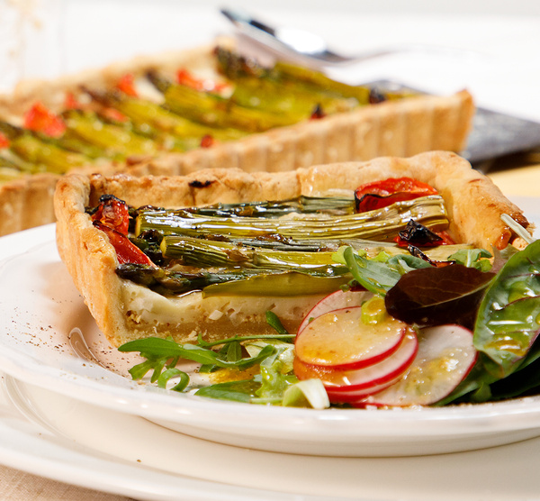 KI generiert: Gemüsequiche mit Spargel und Tomaten, serviert mit einem grünen Salat und Radieschen.