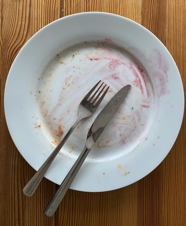 KI generiert: Leerer Teller mit Gabel und Messer, Essensreste darauf.