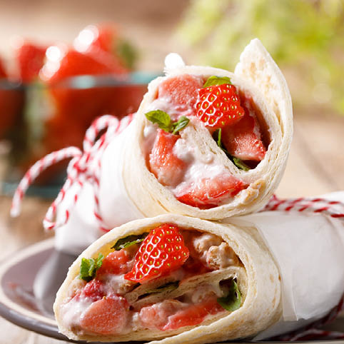 KI generiert: Wraps gefüllt mit Erdbeeren und Sahne, dekorativ angerichtet auf einem Teller.