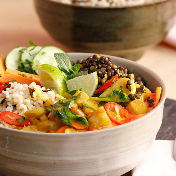 KI generiert: Eine Schüssel mit Gemüse-Curry, Reis, Linsen, Limette und frischen Kräutern.