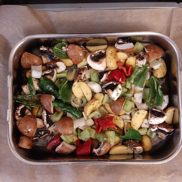 KI generiert: Bunte Gemüse-Mischung mit Pilzen und Kartoffeln in einer Backform auf Backpapier.