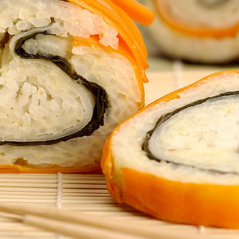 KI generiert: Nahaufnahme von Sushi-Rollen auf einer Bambusmatte mit Essstäbchen.