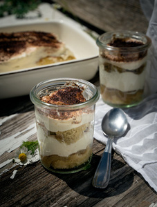 KI generiert: Ein Glas Schokoladenmousse, garniert mit Beeren und Minze, auf einem rustikalen Holztisch.
