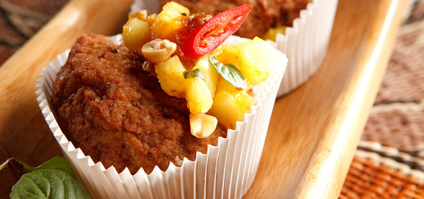 KI generiert: Herzhafte Muffins mit Toppings aus Ananas, Chili und Erdnüssen in Papierförmchen.