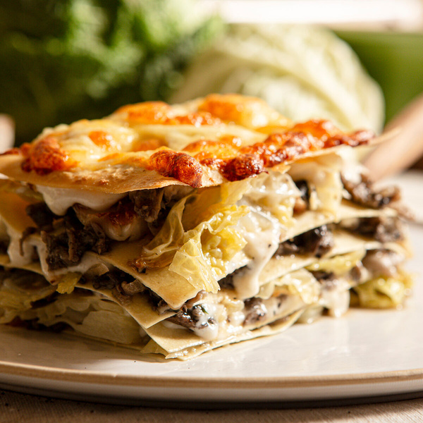 KI generiert: Ein Stück Lasagne mit geschmolzenem Käse und Gemüse auf einem Teller.