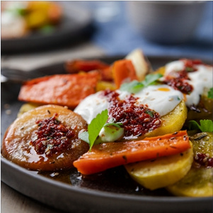 KI generiert: Das Bild zeigt einen in zwei Hälften geschnittenen Butternut-Kürbis auf einem Holzschneidebrett mit herzförmiger Aussparung. Der Kürbis ist leuchtend orange und hat sichtbare Kerne.