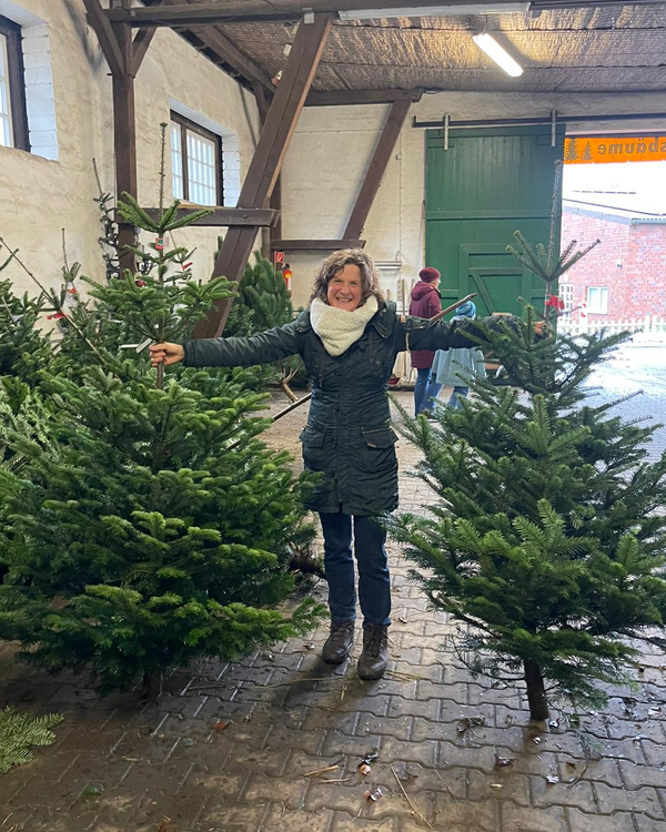 KI generiert: Eine Person steht zwischen zwei Weihnachtsbäumen in einer Scheune.