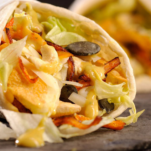 KI generiert: Ein gefüllter Wrap mit Salat, Karottenstreifen und Kürbiskernen.