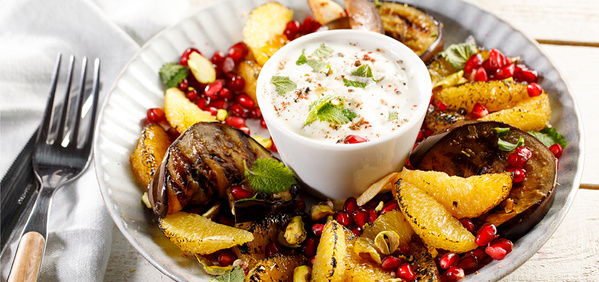 KI generiert: Ein Teller mit gegrilltem Gemüse, Orangen, Granatapfelkernen und einem Dip in der Mitte.