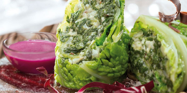 KI generiert: Kohlroulade mit grüner Füllung neben Schälchen mit pinkfarbener Sauce.