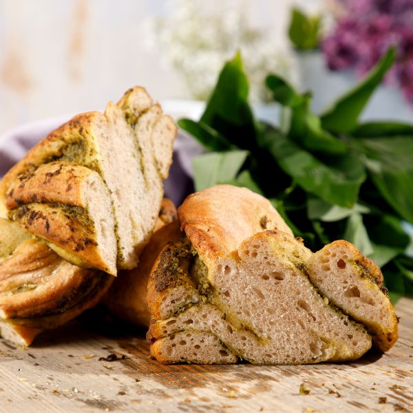 KI generiert: Frisch gebackenes Brot mit Kräuterfüllung, im Hintergrund grüne Blätter.