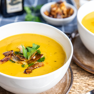 KI generiert: Das Bild zeigt ein Dessert im Glas, das mit einer Löffelportion Croquant und einem Blatt grüne Dekoration versehen ist. Im Hintergrund ist unscharf grüne Dekoration sichtbar.