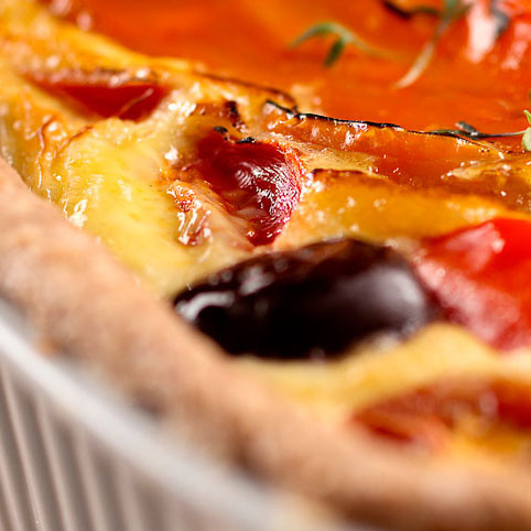 KI generiert: Nahaufnahme einer Quiche mit geröstetem Gemüse.