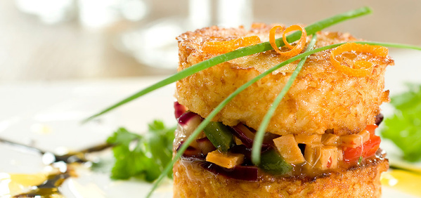 KI generiert: Ein kunstvoll angerichtetes Gericht mit geschichtetem Gemüse und knusprigen Reiskuchen, garniert mit Schnittlauch.